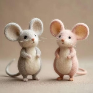 Puede incluir: Dos figuras de ratones de fieltro. Uno es gris con orejas grandes, una nariz rosa y bigotes largos. El otro es rosa con características similares. Ambos tienen brazos y piernas pequeños y están de pie.