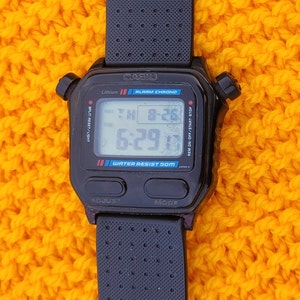 Puede incluir: Reloj de pulsera digital negro Casio con una correa negra. La esfera del reloj muestra la hora, la fecha y el d&iacute;a de la semana. El reloj es resistente al agua hasta 50 metros. El reloj tiene un cron&oacute;metro de fracciones de segundo, alarma y funciones de cron&oacute;grafo.