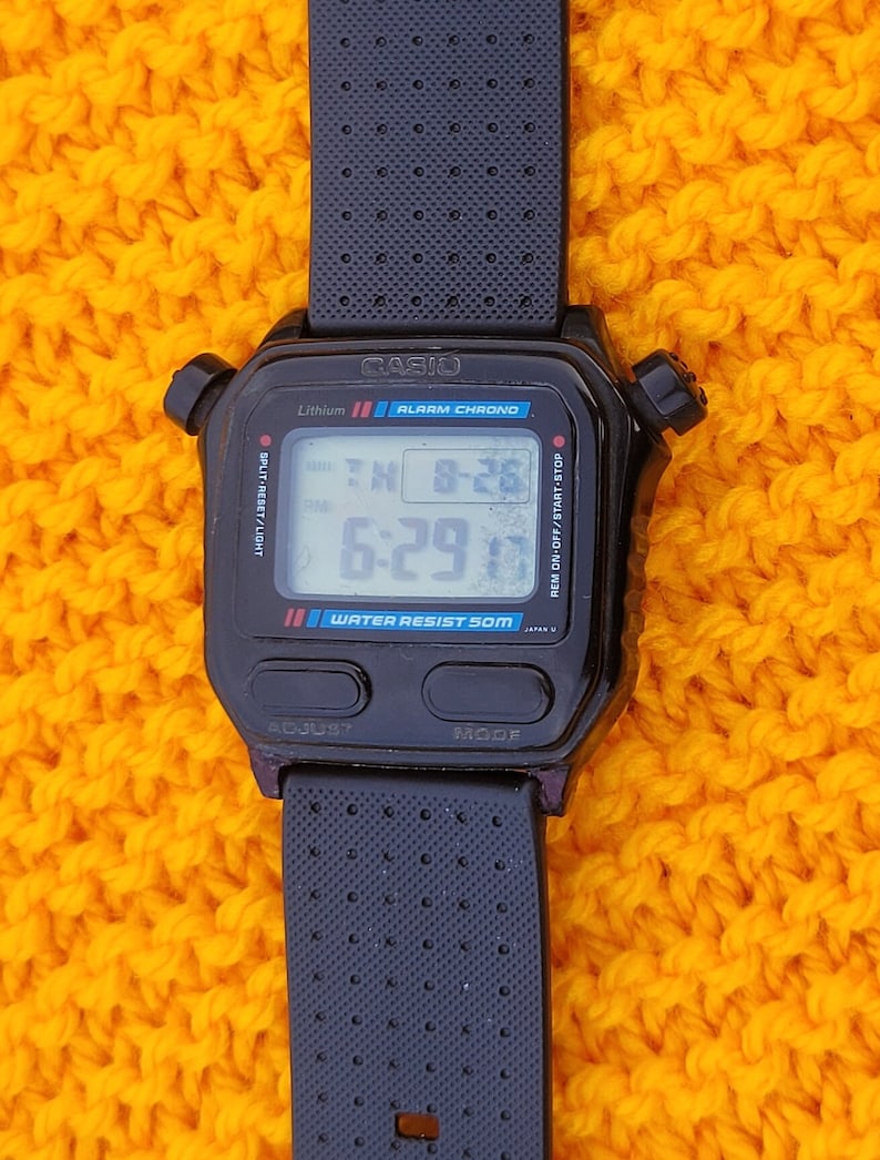 Puede incluir: Reloj de pulsera digital negro Casio con una correa negra. La esfera del reloj muestra la hora, la fecha y el d&iacute;a de la semana. El reloj es resistente al agua hasta 50 metros. El reloj tiene un cron&oacute;metro de fracciones de segundo, alarma y funciones de cron&oacute;grafo.