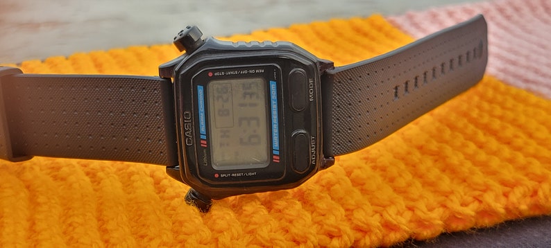 Puede incluir: Un reloj digital Casio negro con una correa de goma negra. La esfera del reloj muestra la hora, la fecha y el d&iacute;a de la semana.