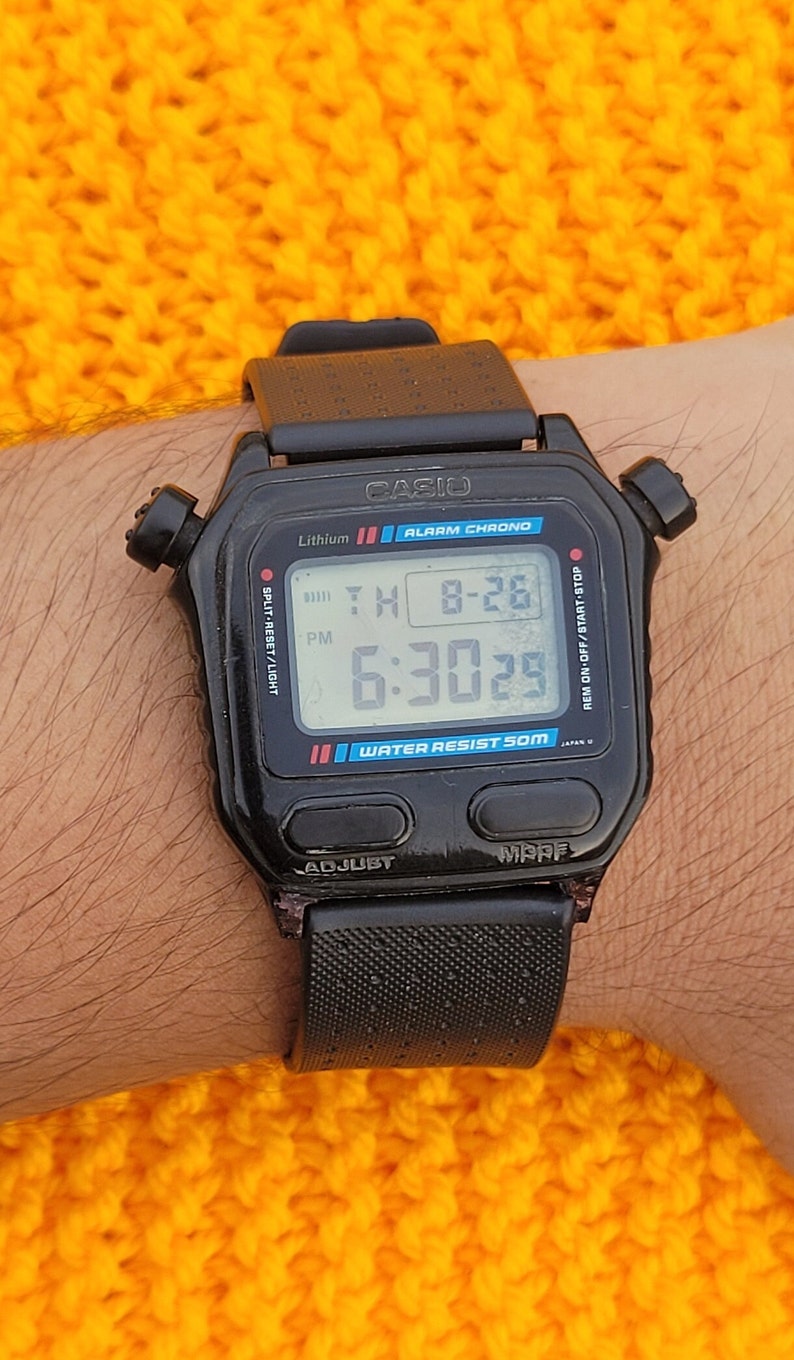 Puede incluir: Un reloj digital Casio negro con una correa negra. La esfera del reloj muestra la hora, la fecha y el d&iacute;a de la semana. El reloj es resistente al agua hasta 50 metros. El reloj tiene un bot&oacute;n split-reset/light, un bot&oacute;n rem on-off/start-stop y un bot&oacute;n adjust.