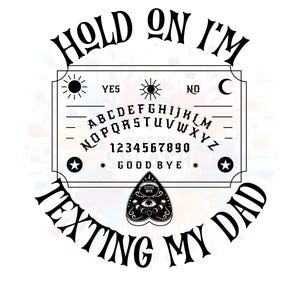May include: A white Ouija board with black lettering and a planchette. The board has the text "HOLD ON I'M TEXTING MY DAD" in a circular design. The board includes the alphabet, numbers, and the words "YES", "NO", and "GOOD BYE".
