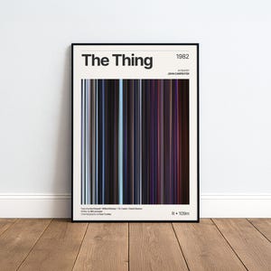 Könnte beinhalten: Ein gerahmtes Filmplakat für den Film The Thing aus dem Jahr 1982 unter der Regie von John Carpenter. Das Design zeigt eine zentrale vertikale Grafik aus dünnen, dunkelblauen, schwarzen und roten Linien sowie weißen Text mit Besetzungsdetails.