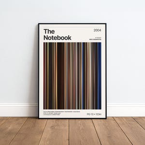 May include: A framed film poster for The Notebook, released in 2004. The design features a central vertical colour palette of brown, blue, and tan stripes representing the film, with text including the title, director, cast, and PG-13 rating.