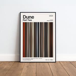 Puede incluir: Un póster de película enmarcado de Dune Part Two 2024, con un gráfico central vertical estilo código de barras de rayas marrones, negras, naranjas y grises. El texto incluye el título, el director y la clasificación PG-13 166m.