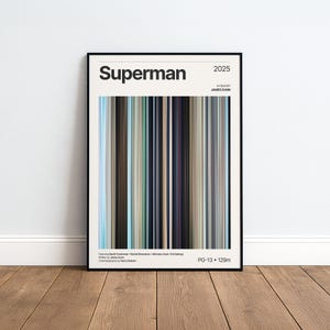 Puede incluir: Un póster de película enmarcado para la película Superman de 2025, dirigida por James Gunn. El diseño presenta un gráfico central vertical estilo código de barras compuesto por finas rayas multicolores en tonos azul, marrón, negro y gris, con texto.