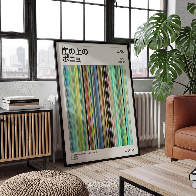 May include: A framed poster featuring the Japanese title "Ponyo on the Cliff by the Sea" with vertical stripes in various colors. The poster is in a black frame and is displayed in a living room setting with a window and a large plant.