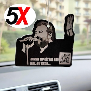 May include: Black car air freshener featuring a singer with a microphone, with the text "BIRAK AY GITSIN SEN KAL BU GECE..." and a QR code. A white and red "5X" logo is in the upper left corner. The air freshener hangs from a string.