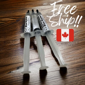 May include: Three clear plastic syringes filled with a blue liquid. The syringes are labelled "Blue Oyster" and have a black cap on the tip. The syringes are lying on a wooden surface. Free Ship!! is written in white on a red background with a Canadian flag.