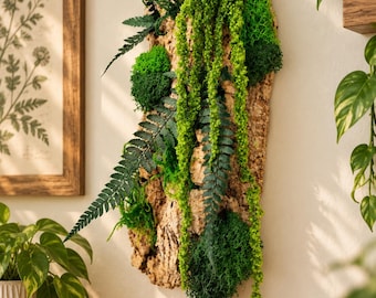 May include: A vertical wall hanging featuring a textured, light brown cork bark slab adorned with various shades of vibrant green preserved moss and artificial fern fronds. The arrangement includes cascading bright green foliage.