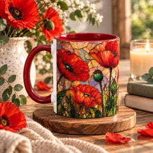May include: A ceramic mug featuring a vibrant stained-glass style print of red poppy flowers with green stems and leaves. The mug has a solid deep red handle and a matching red interior, showcasing a detailed floral pattern throughout the exterior.