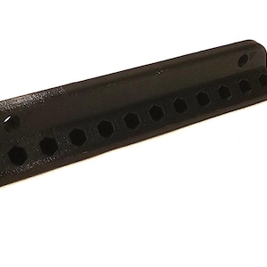 Op de afbeelding: Een zwarte plastic gereedschaphouder met 12 zeshoekige gaten.