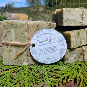 May include: Handcrafted Cedar & Pine bar soap, wrapped with twine and a round tag. The tag reads "Grand Fir Homestead" and lists ingredients. The soap is a light green color and weighs 4-5 oz.