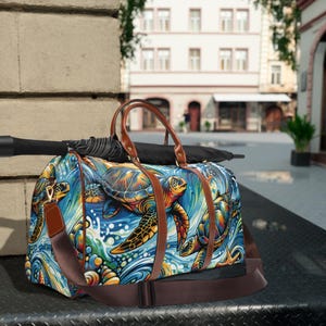 May include: A duffel bag featuring a vibrant sea turtle design. The bag has brown leather handles and a matching shoulder strap. The artwork depicts colorful turtles swimming in a blue ocean with waves and seashells.