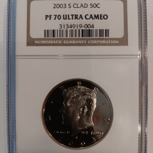 Peut inclure: Une pièce de 50C de 2003 S Clad, classée PF 70 Ultra Cameo, dans un boîtier de protection transparent. La pièce présente un profil d'homme et l'inscription "IN GOD WE TRUST". Le boîtier est étiqueté "NUMISMATIC GUARANTY CORPORATION".