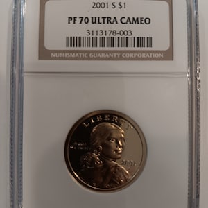 Peut inclure: Une pièce de 1 dollar S 2001, classée PF 70 Ultra Cameo, dans un boîtier de protection transparent. La pièce présente un portrait et le mot "LIBERTY". Le boîtier porte l'inscription "NUMISMATIC GUARANTY CORPORATION".