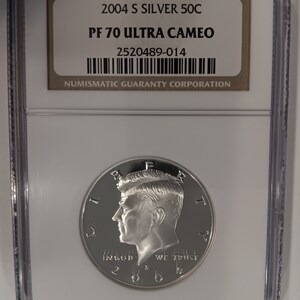 Peut inclure: Une pièce de 50C en argent de 2004 S, classée PF 70 Ultra Cameo, dans un boîtier de protection. La pièce présente un profil d'homme et les inscriptions "IN GOD WE TRUST" et "2004". Le boîtier porte une étiquette "NUMISMATIC GUARANTY CORPORATION".