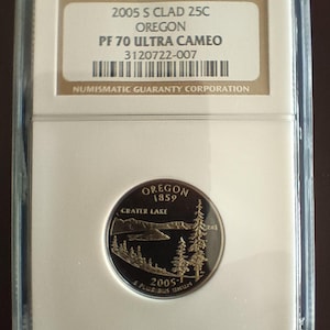 Peut inclure: Une pièce de monnaie Oregon 2005 S Clad 25C, classée PF 70 Ultra Cameo, dans un étui de protection. La pièce représente Crater Lake et des arbres. L'étui comprend le texte "NUMISMATIC GUARANTY CORPORATION".