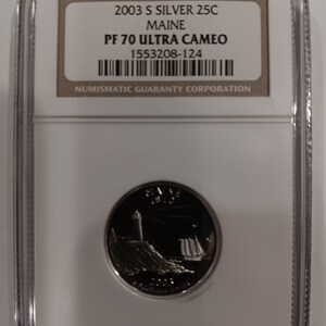 Peut inclure: Une pièce de monnaie en argent de 25 cents du Maine de 2003, dans un étui de protection. La pièce représente un phare et un voilier. L'étui porte l'inscription "2003 S SILVER 25C MAINE PF 70 ULTRA CAMEO".