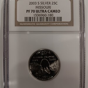 Peut inclure: Une pièce de monnaie Missouri 25C en argent S de 2003, dans un étui de protection. La pièce présente un motif détaillé avec le texte "Corps of Discovery" et les années 1804 et 2004. L'étui comprend une étiquette avec des informations de classement.