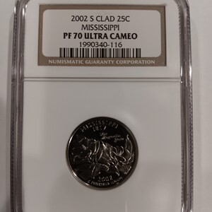 Peut inclure: Une pièce de monnaie de 25 cents Mississippi 2002 S Clad, classée PF 70 Ultra Cameo, dans un boîtier de protection. La pièce présente un motif avec le nom de l'État, l'année et des éléments floraux. Le boîtier contient une étiquette avec des informations de classement.