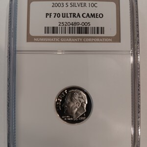 Peut inclure: Une pièce de monnaie 2003 S Silver 10C, classée PF 70 Ultra Cameo, dans un boîtier de protection transparent. La pièce présente un profil d'homme et l'année 2003. Le boîtier comprend une étiquette avec le logo Numismatic Guaranty Corporation.