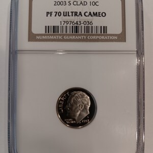 Peut inclure: Une pièce de monnaie 2003 S Clad 10C, classée PF 70 Ultra Cameo, dans un boîtier de protection transparent. La pièce présente un profil de personne et le mot "LIBERTY". Le boîtier est étiqueté par Numismatic Guaranty Corporation.