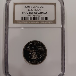 Peut inclure: Une pièce de monnaie Michigan 2004 S Clad 25C, classée PF 70 Ultra Cameo, dans un boîtier de protection. La pièce représente l'État du Michigan, avec le texte "Great Lakes State" et l'année 2004.