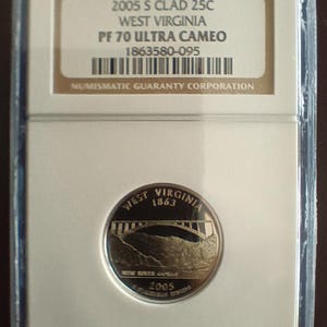 Peut inclure: Une pièce de 25 cents de la Virginie-Occidentale de 2005, dans un étui de protection. La pièce représente un pont et le texte "West Virginia 1863". L'étui porte l'inscription "2005 S CLAD 25C" et "PF 70 ULTRA CAMEO".