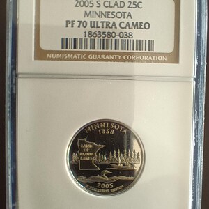 Peut inclure: Une pièce de monnaie de 25 cents du Minnesota de 2005, dans un étui de protection. La pièce représente un paysage lacustre avec un huard et le texte "Minnesota 1858". L'étui indique le grade et la certification de la pièce.