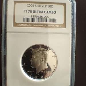 Peut inclure: Une pièce de monnaie 2005 S Silver 50C, classée PF 70 Ultra Cameo, dans un boîtier de protection. La pièce présente un profil d'une personne et l'inscription "IN GOD WE TRUST". Le boîtier porte la mention "NUMISMATIC GUARANTY CORPORATION".
