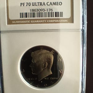 Peut inclure: Une pièce de monnaie 2005 S Clad 50C, classée PF 70 Ultra Cameo, dans un étui de protection. La pièce présente un profil d'homme et les mots "IN GOD WE TRUST". Le support affiche le numéro de série 1863093-176 et le logo Numismatic Guaranty Corporation.