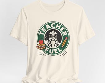 Könnte beinhalten: Cremefarbenes T-Shirt mit einem grün-schwarzen Grafikdesign, das einem Café-Logo ähnelt. Das Design zeigt eine Lehrer-Silhouette, eine Kaffeetasse, einen Apfel, Bücher und einen Bleistift mit dem Schriftzug "TEACHER FUEL".
