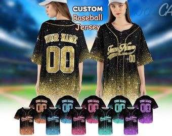 Pode incluir: Uma camisa de beisebol preta com glitter dourado e o texto "YOUR NAME" e "00" nas costas. A camisa é mostrada em um modelo com um fundo preto.