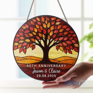 Op de afbeelding: Een ronde glas-in-lood afbeelding van een boom met rode, oranje en gele bladeren. De tekst "40TH ANNIVERSARY Jason & Claire 29.08.2025" staat onderaan. Opgehangen aan een ketting.
