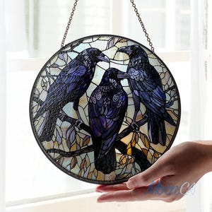 May include: A stained glass window hanging features three black ravens perched on branches with a detailed background of leaves and vines.