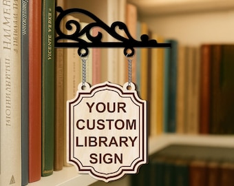 May include: A wooden sign with the text "YOUR CUSTOM LIBRARY SIGN" hangs from a black metal bracket. The sign is light brown with a dark brown border and text. The bracket has a decorative scroll design and is attached to a bookshelf.