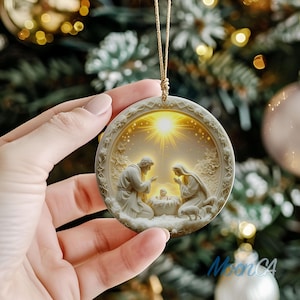 May include: A round, off-white Christmas ornament with a religious scene. The ornament depicts a nativity scene with Joseph, Mary, and baby Jesus. The ornament is held by a gold string and has a detailed, embossed border.