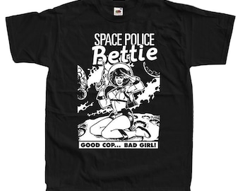 May include: Black t-shirt with a white graphic of a woman in a space suit holding a gun. The text "Space Police Bettie" is above the image and "Good Cop... Bad Girl!" is below the image.