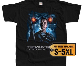 May include: Black t-shirt featuring a graphic of Arnold Schwarzenegger as the Terminator from the movie Terminator 2: Judgment Day. The graphic shows Schwarzenegger's face with red glowing eyes and a robotic endoskeleton behind him. The text "Terminator Judgment Day" is printed below the graphic. The text "All Sizes Available S-5XL" is printed on a yellow tag.