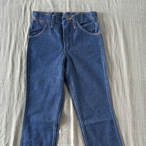 Op de afbeelding: Een spijkerbroek van blauwe denim met een klassiek ontwerp met vijf zakken. De jeans hebben een knoop- en ritssluiting, riemlussen en een rechte pijp. De denim heeft een medium wassing en de jeans liggen plat.
