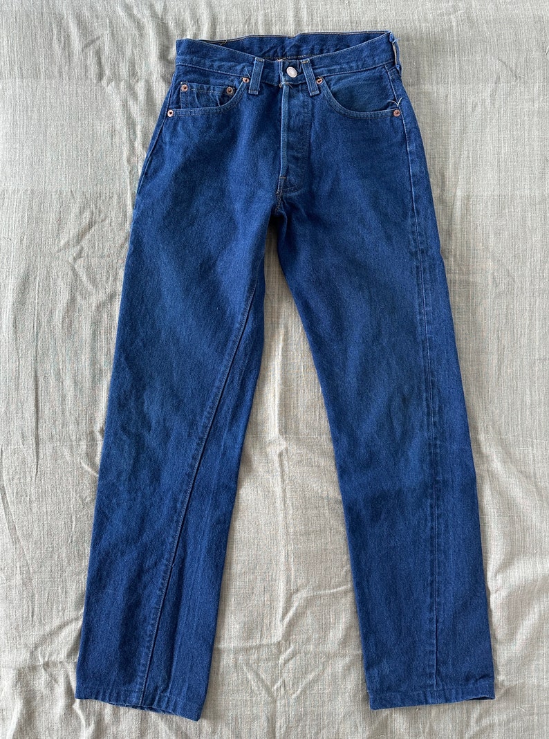 May include: A pair of dark blue denim jeans with a classic five-pocket style. The jeans have a straight leg and a button fly.