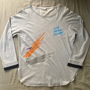 May include: Grey long-sleeved shirt with a palm tree graphic and the text "Let the Wine Take That Fantasy".