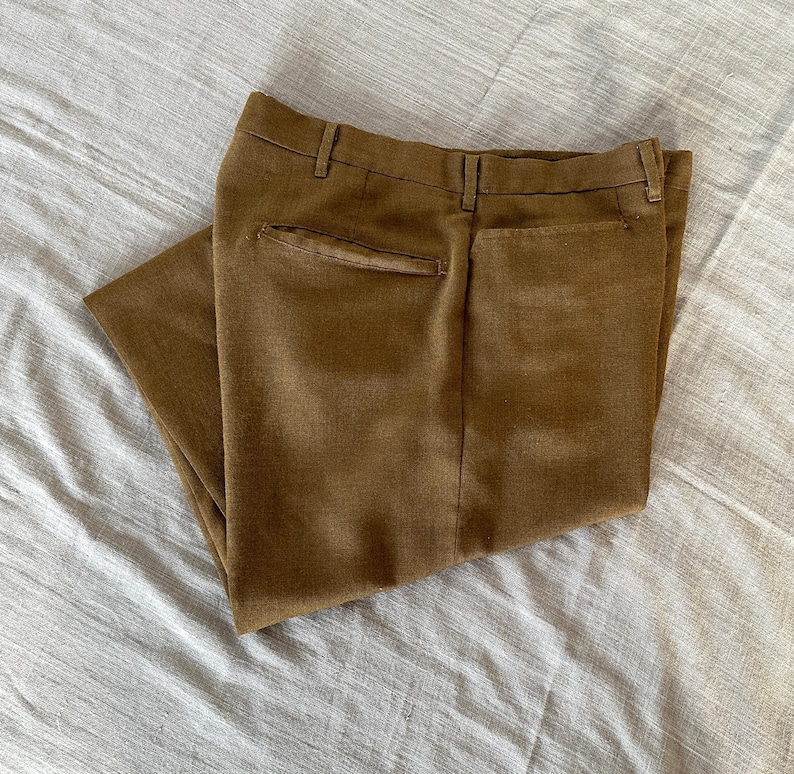 May include: A pair of brown pants folded in half, showing the back pockets. The pants are made of a textured fabric.