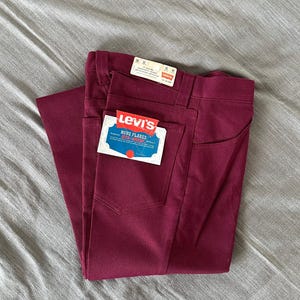 Könnte beinhalten: Eine dunkelrote Levi's Jeans mit einem Etikett mit der Aufschrift "Novo Flares Sta-Prest".