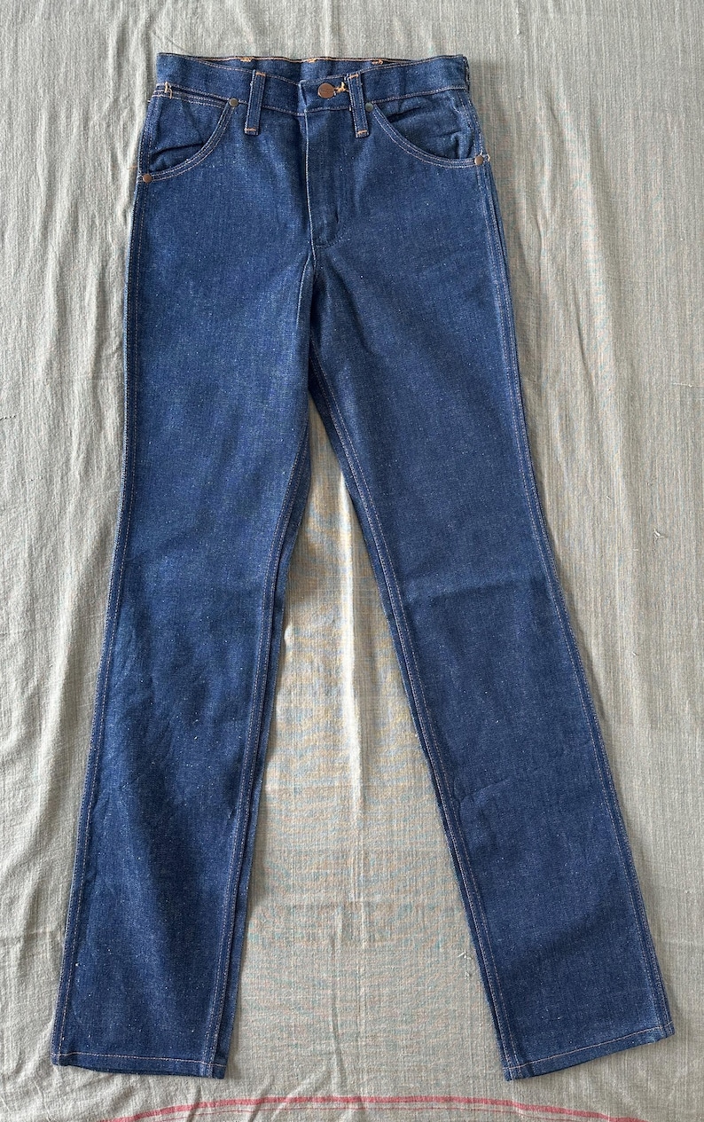 Op de afbeelding: Een spijkerbroek van blauwe denim met een klassiek ontwerp met vijf zakken. De jeans hebben een knoop- en ritssluiting, riemlussen en een rechte pijp. De denim heeft een medium wassing en de jeans liggen plat.