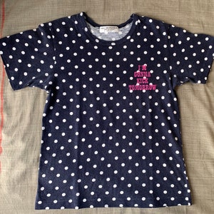 May include: A navy blue t-shirt with white polka dots and the text "I'm gonna kick tomorrow" in pink.