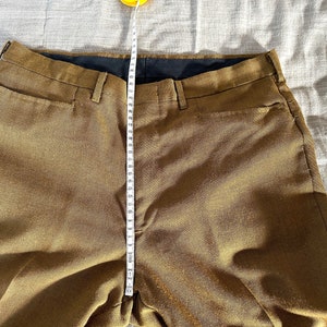 May include: A pair of brown pants with a black waistband and a measuring tape running down the center.
