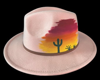 Custom hand painted light pink felt fedora with vivid sunset and cactus silhouettes. Adjustable inner strap, one size fits most.