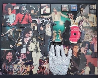 May include: A framed collage of Michael Jackson photos and memorabilia. The collage includes photos of Jackson in various stages of his career, as well as album covers, concert posters, and other items. The collage is framed in a black frame and has a white mat.